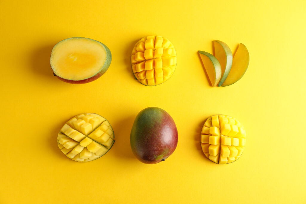 Flat lay composition with ripe mangoes on color background